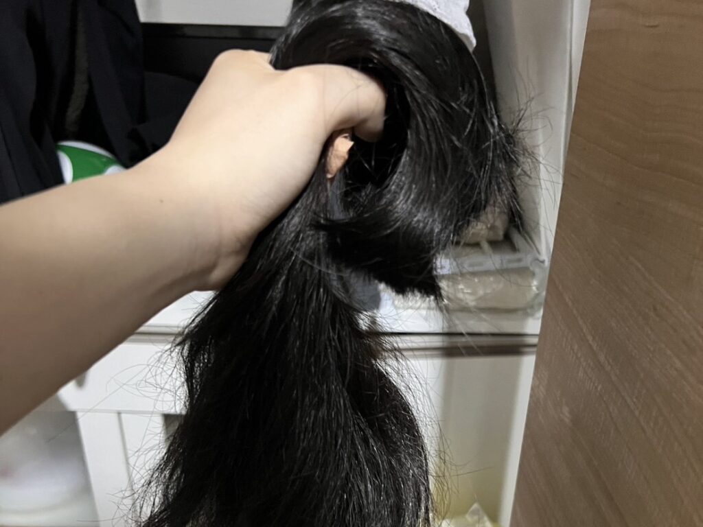 部屋の中で、切った長い髪を持つ手